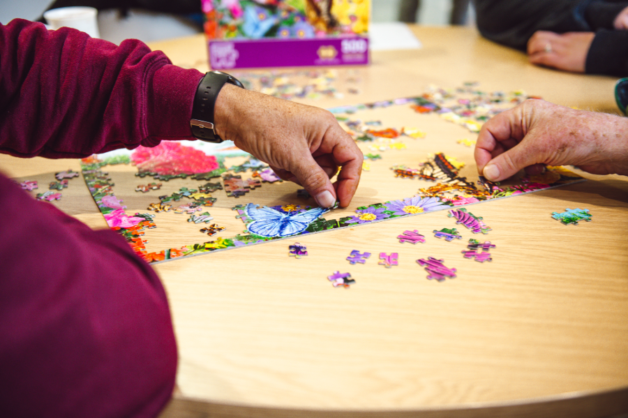 close up of two people's hands doing a jigsaw